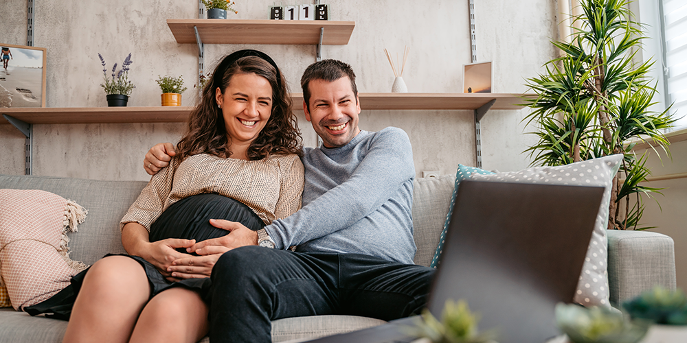 happy pregnant couple looking at tablet