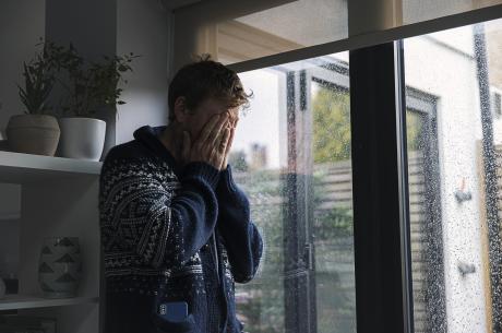 Man by window - head in hands - stock photo
