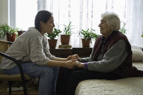 Young woman holding old woman&#039;s hands during conversation