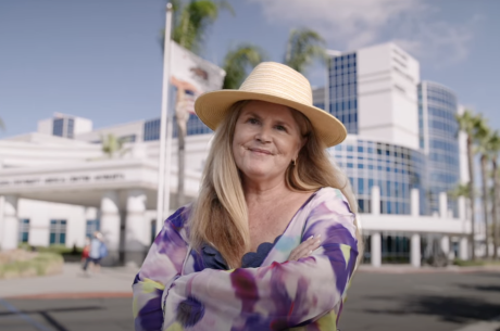 A woman in a floral dress stands in front of Loma Linda University Healthy Murrieta Center