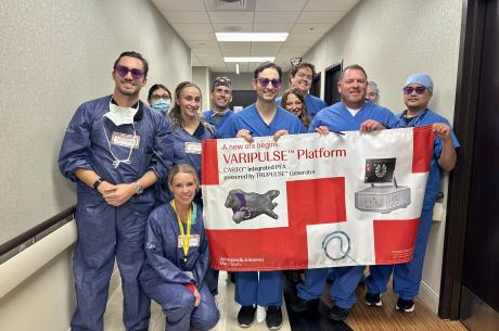 Cardiology team stand together in a hallway holding a large banner that reads “VARIPULSE Platform.” 