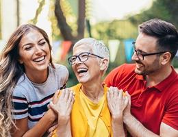 Mom, daughter, and son outdoors smiling and holding hands