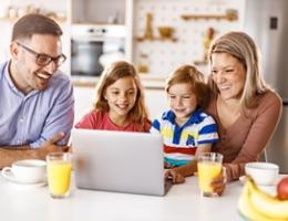 family gathered around the table viewing a laptop